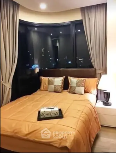 Luxurious bedroom with large window offering stunning city night view, elegant decor, and cozy ambiance.