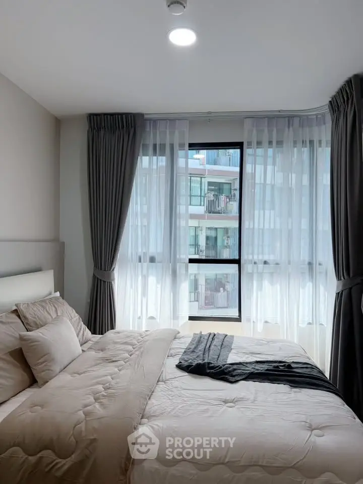 Modern bedroom with large window and elegant curtains in a stylish apartment.