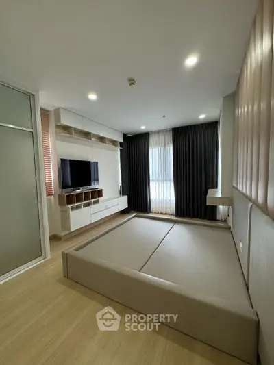 Modern bedroom with built-in TV and storage, featuring sleek design and ample natural light.