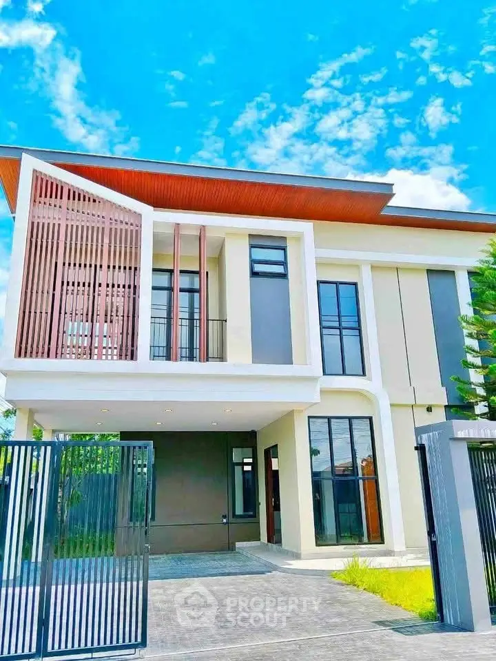 Modern two-story house with sleek design and large windows under a clear blue sky.