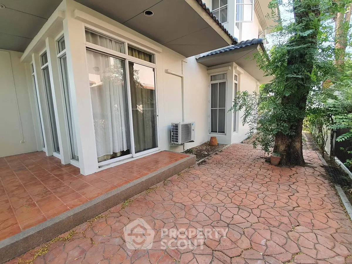 Charming exterior view of a modern home with patio and lush greenery, perfect for outdoor relaxation.