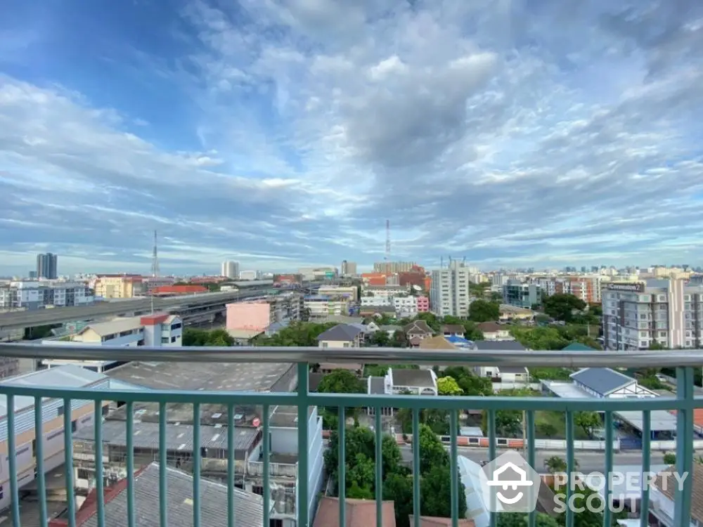 Expansive cityscape view from a high-rise balcony under a dramatic cloud-filled sky, perfect for urban living enthusiasts.