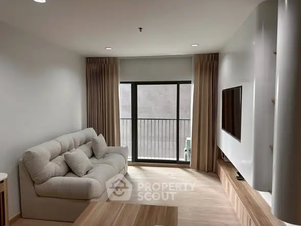 Modern living room with cozy sofa and large TV, featuring elegant curtains and wooden flooring.