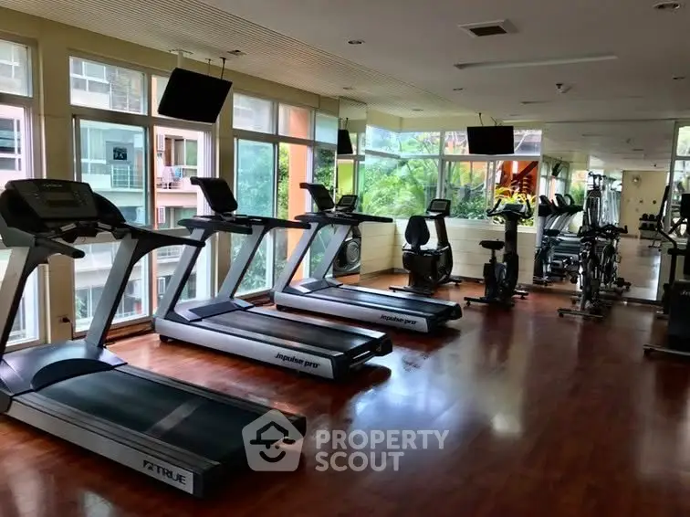 Spacious gym with modern equipment and large windows offering a scenic view, perfect for fitness enthusiasts.