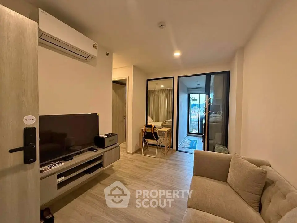 Modern living room with cozy sofa and TV, featuring a small dining area and balcony access.
