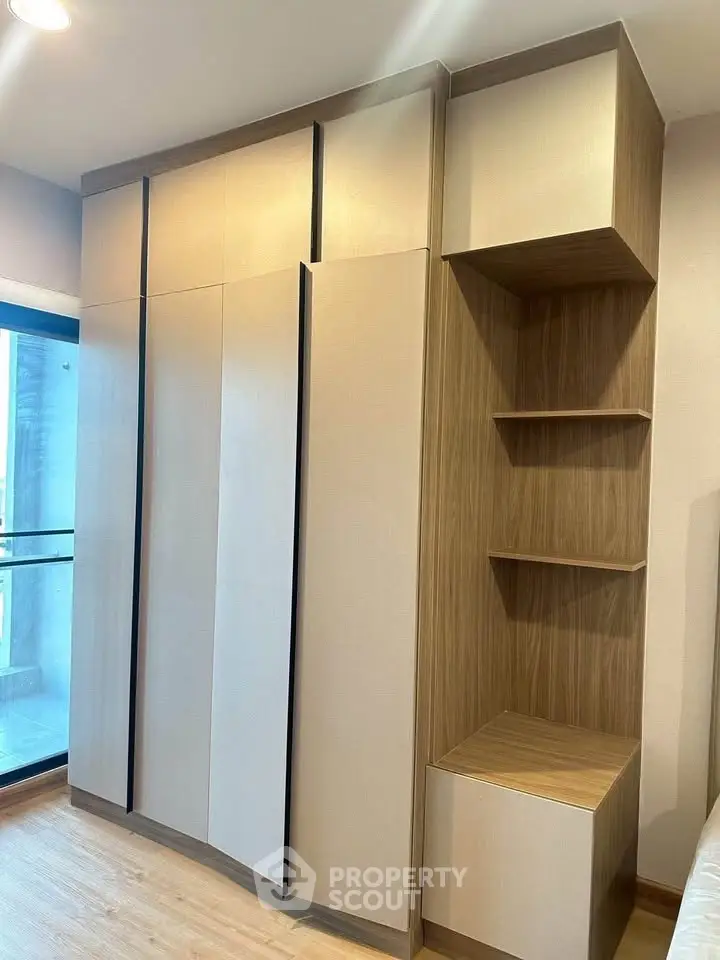 Modern bedroom with built-in wooden wardrobe and shelving, featuring sleek design and ample storage space.