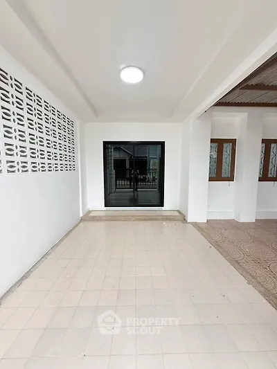 Spacious covered patio area with tiled flooring and modern sliding glass doors, perfect for outdoor relaxation.