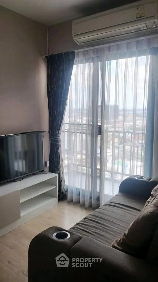 Cozy living room with city view, featuring a comfortable sofa and modern entertainment setup.