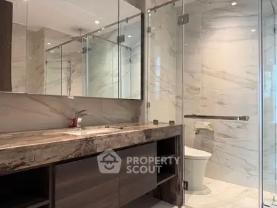 Luxurious modern bathroom with marble finishes and glass shower enclosure.