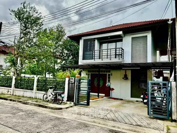 Charming two-story house with balcony and gated driveway in a serene neighborhood.