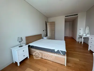 Spacious modern bedroom with wooden flooring and minimalist furniture