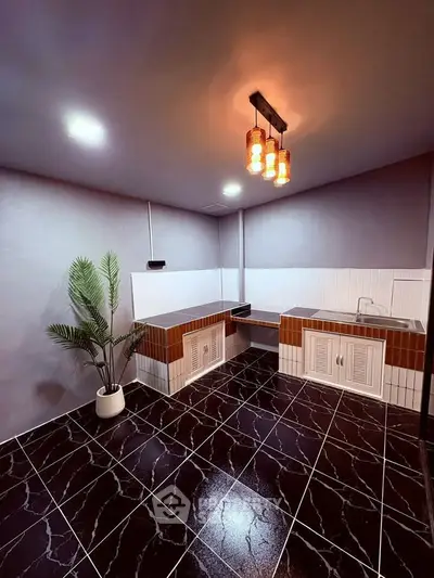 Modern kitchen with stylish lighting and sleek black tile flooring