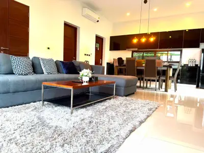 Spacious modern living room with plush gray sofa, elegant dining area, and sleek kitchen in open layout.
