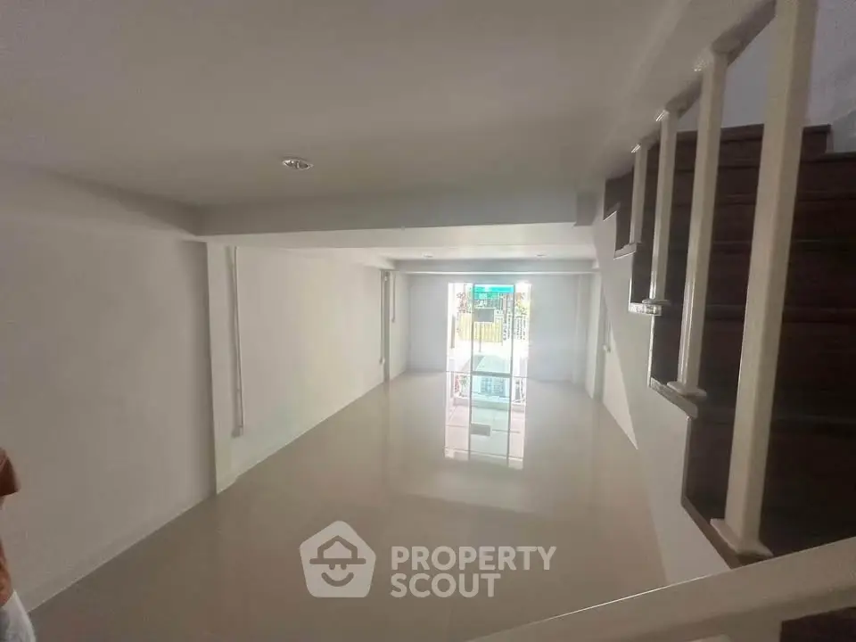 Spacious modern living room with sleek staircase and large window for natural light.