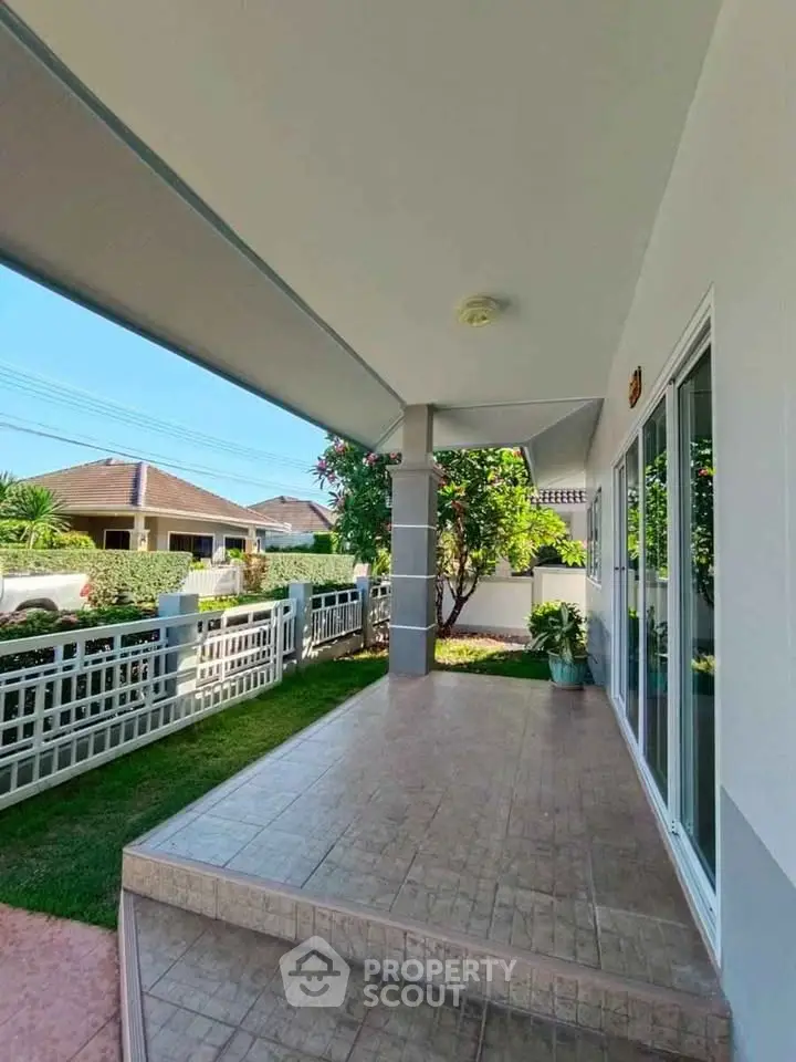 Charming home entrance with tiled porch and lush garden view