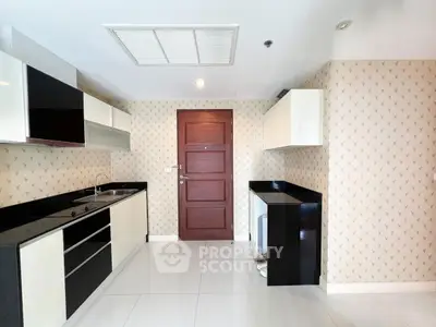 Modern kitchen with sleek black and white cabinetry and stylish wallpaper.