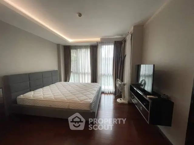 Spacious bedroom with modern decor and large windows for natural light.