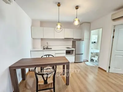 Modern kitchen with dining area featuring sleek cabinetry and stylish lighting