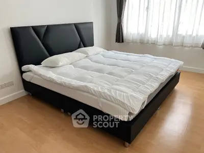Spacious bedroom with modern black bed frame and large window for natural light.