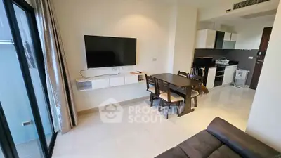 Modern living room with wall-mounted TV and sleek kitchen in open layout apartment.