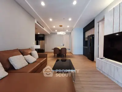 Spacious modern living room with elegant brown leather sofa and sleek black appliances.