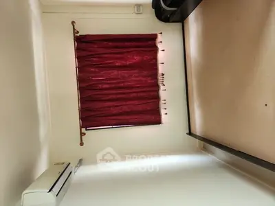 Minimalist bedroom with red curtains and air conditioning unit.