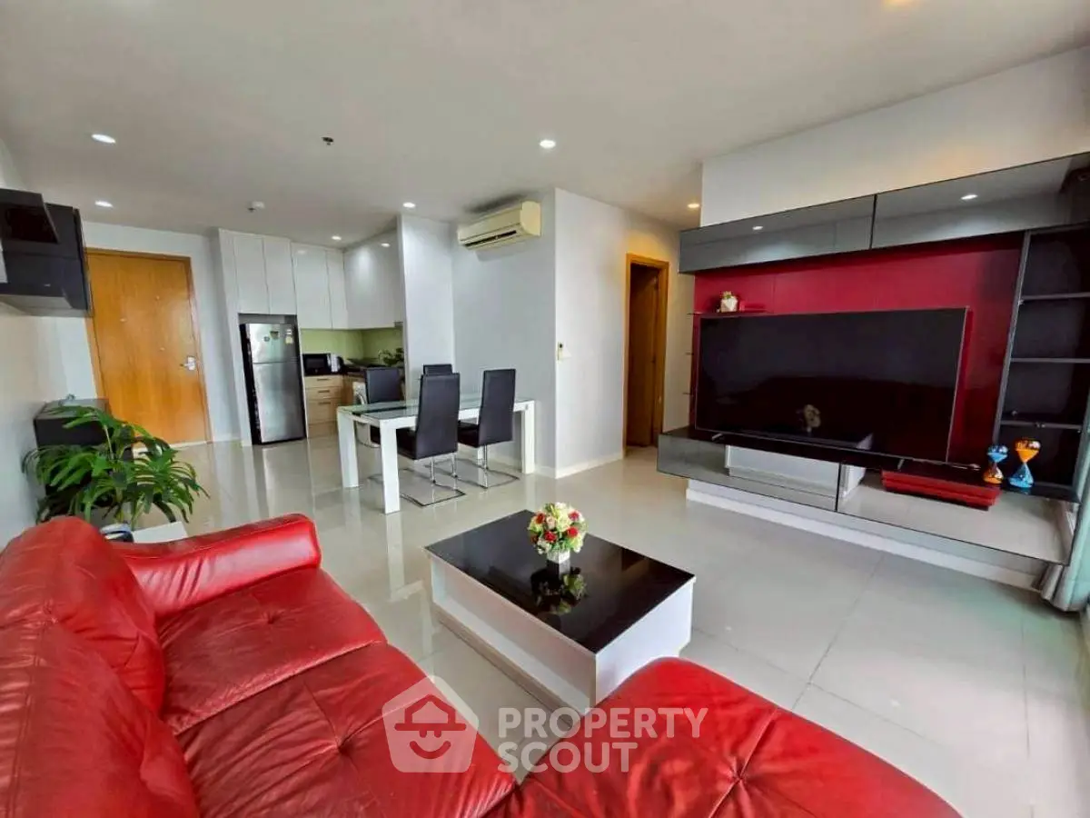 Spacious modern living room with red leather sofa and large TV