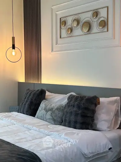 Luxurious bedroom with elegant decor and plush bedding, featuring modern lighting and stylish wall art.