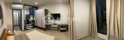 Modern bedroom with TV and view into stylish kitchen area