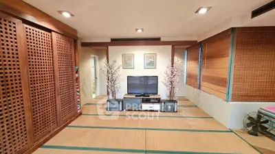 Spacious living room with tatami flooring and modern TV setup, featuring elegant wooden accents and natural light.