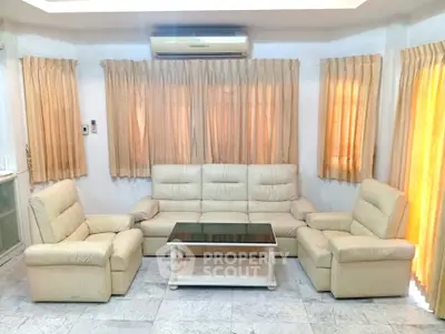 Spacious living room with elegant beige leather sofas and natural light from large windows.
