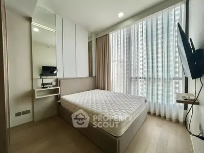 Modern bedroom with large windows and natural light in a high-rise apartment.