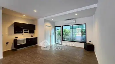 Modern open-plan living room with sleek kitchen and large window view.