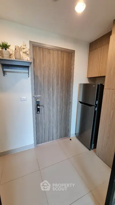 Modern kitchen entrance with sleek wooden door and stainless steel fridge