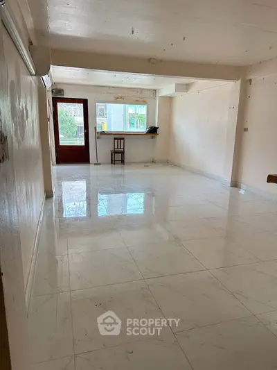 Spacious living room with glossy tiled floors and large windows for natural light.