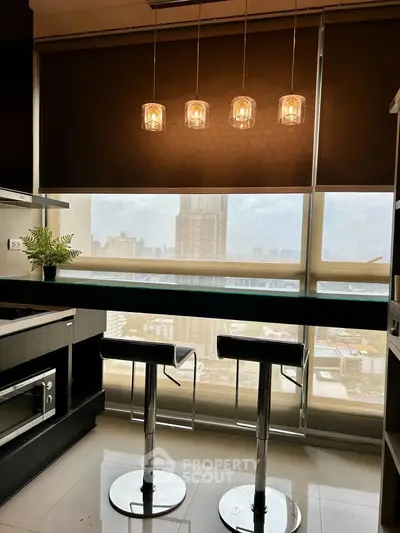 Modern kitchen with city view, featuring sleek bar stools and pendant lighting, perfect for urban living.
