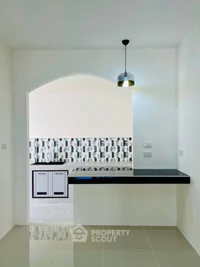 Modern kitchen with sleek black countertop and stylish backsplash in a minimalist design.