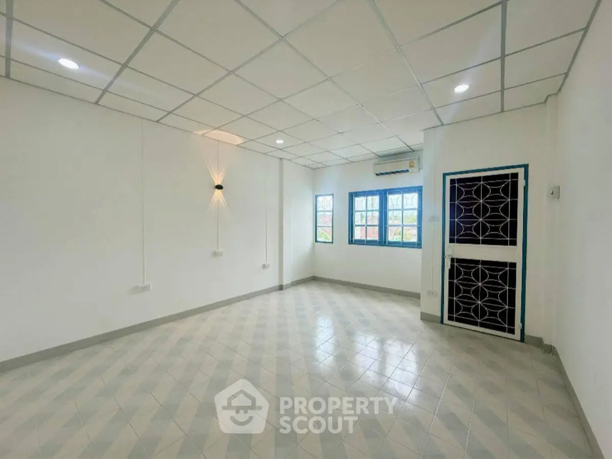 Spacious empty room with tiled flooring and modern lighting, ideal for customization.