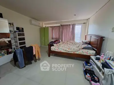 Cozy bedroom with wooden bed, wardrobe, and ample natural light.