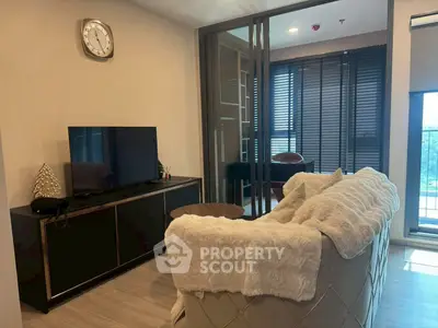 Modern living room with cozy sofa and TV, featuring elegant decor and natural light.