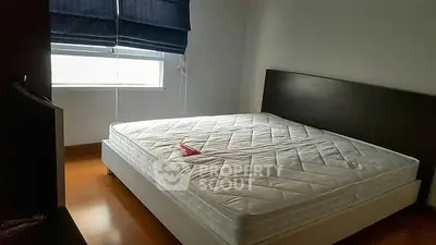Spacious bedroom with large window and modern bed frame.