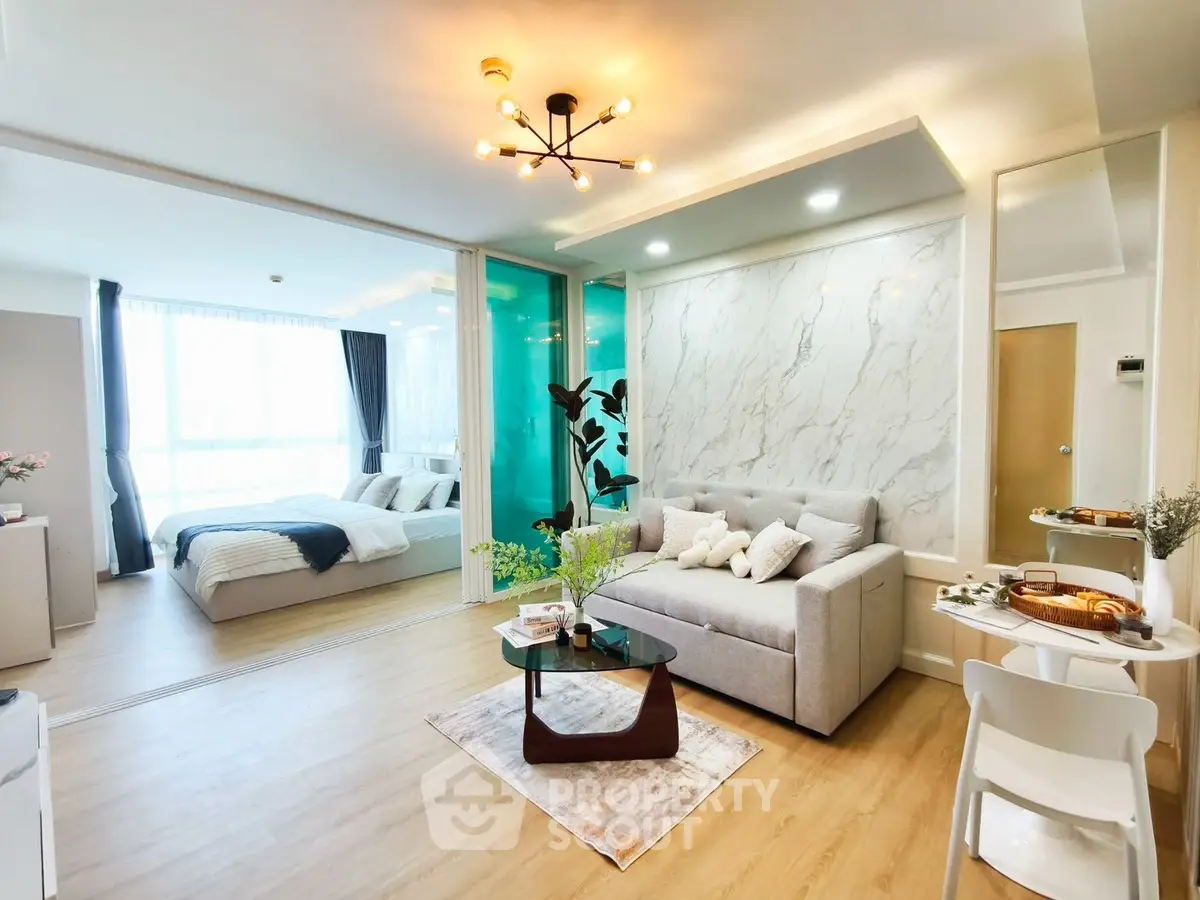 Modern open-plan living room with stylish decor and cozy bedroom view.