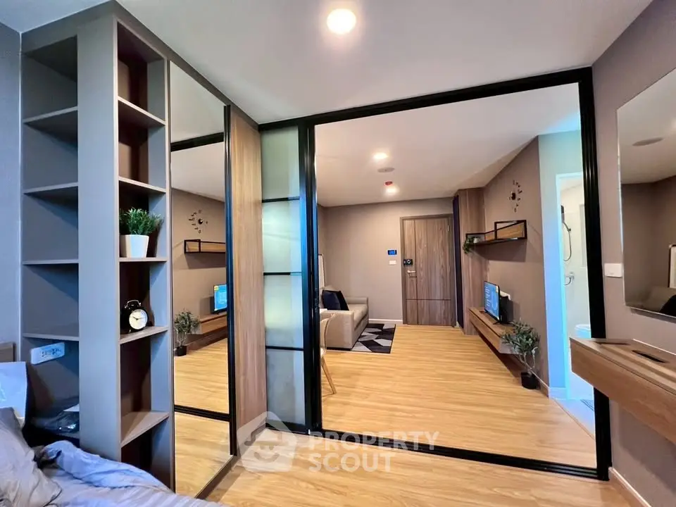 Modern apartment interior with open layout, featuring stylish living room and bedroom with mirrored closet doors.