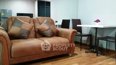 Cozy living room with leather sofa and dining area, perfect for relaxation and entertaining.