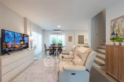 Spacious modern living room with cozy seating and large TV, perfect for relaxation and entertainment.