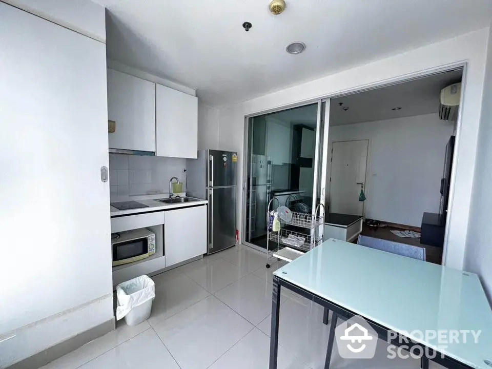 Modern compact kitchen with sleek design and glass dining table in bright apartment