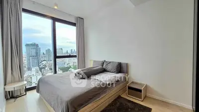 Modern bedroom with stunning city view and large windows in high-rise apartment.