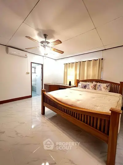 Spacious bedroom with wooden bed and ceiling fan in a cozy home setting.