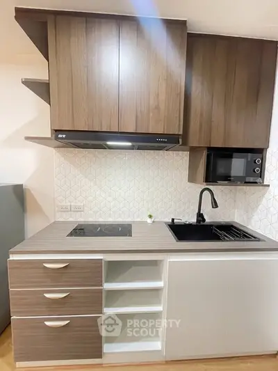 Modern kitchen with sleek cabinetry, induction cooktop, and built-in microwave in stylish apartment.