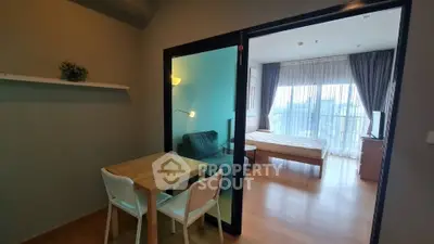 Modern studio apartment with glass partition, cozy dining area, and bright bedroom with city view.